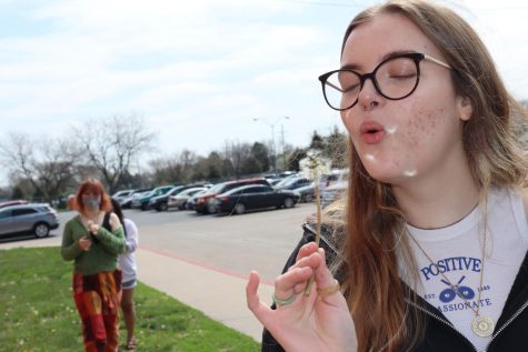 Sophomore Joci Blair celebrates Earth Day by blowing on a dandelion. 