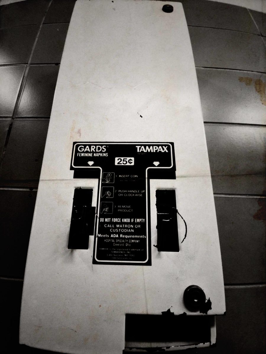 An old, empty menstrual product dispenser is pictured in a restroom at Fremont High School. Students say the lack of accessible menstrual products highlights an ongoing issue with basic hygiene access in schools.