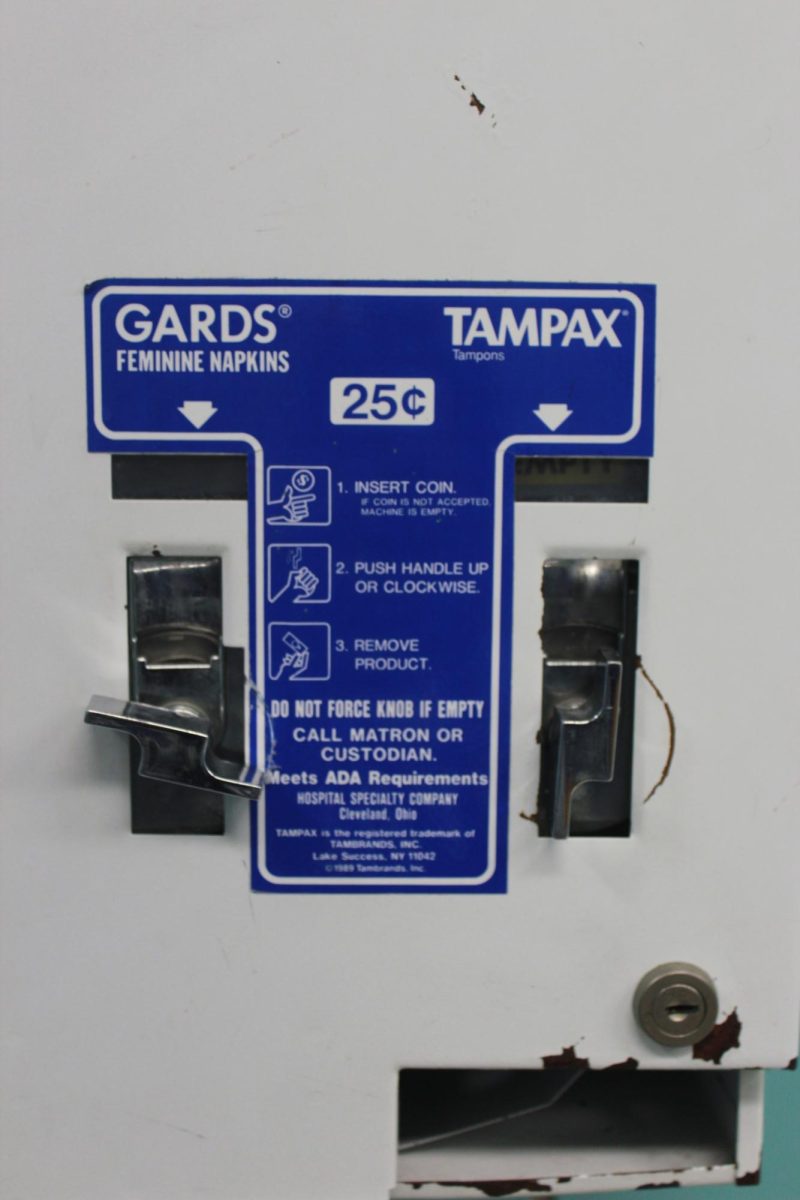 A broken and empty menstrual product dispenser is shown in a restroom at Fremont High School. A student-led investigation found many dispensers throughout the school are unstocked or out of order, leaving students to seek products elsewhere.